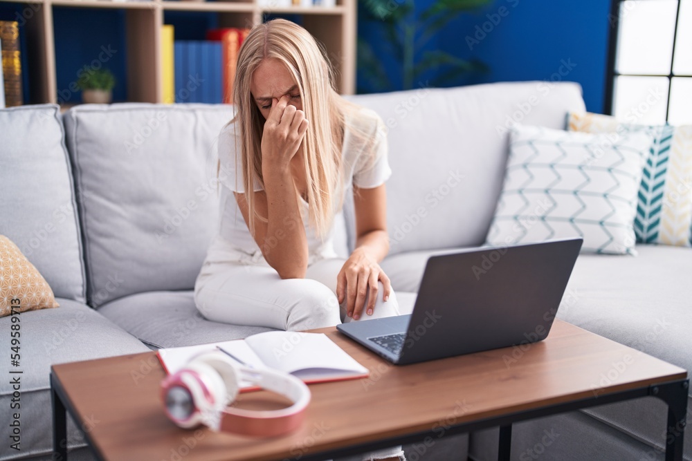 Poster Young blonde woman student stressed sitting on sofa studying at home