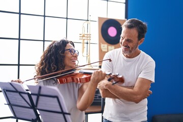 Man and woman violinist having violin lesson at music studio