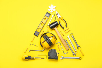 Christmas tree made of builder's tools and snowflake on yellow background