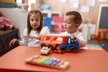 Adorable girl and boy playing with car on table at kindergarten