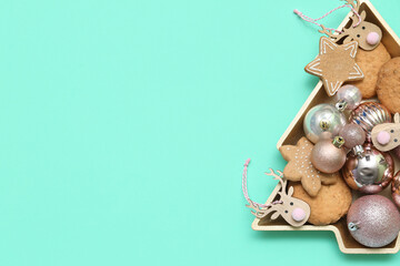 Plate in shape of Christmas tree with cookies and decor on green background