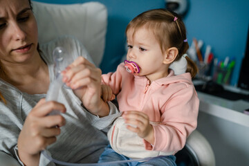 one toddler girl and mother using steam inhaler nebulizer at home