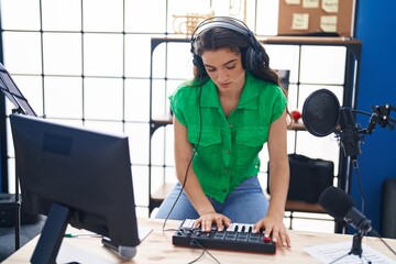 Young hispanic woman musician having dj session at music studio