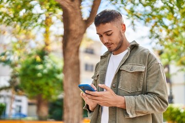Young hispanic man smiling confident using smartphone at park - Powered by Adobe