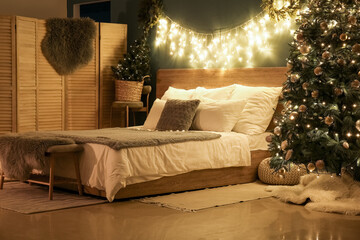 Interior of bedroom with Christmas trees and glowing lights at night