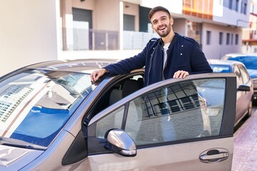 Young hispanic man smiling confident opening car door at street