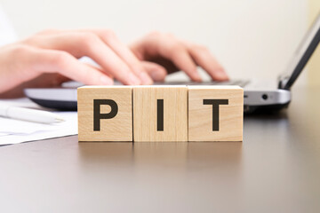 pit - acronym from wooden blocks with letters. background hands on a laptop with blur. business concept. - obrazy, fototapety, plakaty