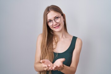 Young caucasian woman standing over white background smiling with hands palms together receiving or giving gesture. hold and protection