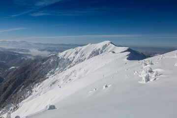 Fototapeta na wymiar Snowy mountain against the background of a large massive Marmaros mountain range. Winter mountains landscape outdoor concept