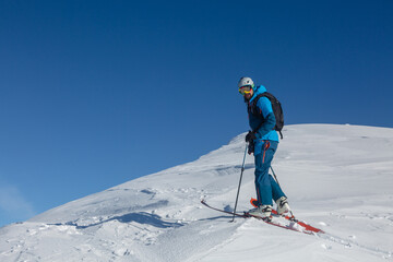 Fototapeta na wymiar An active ski-tour rider on a winter trail in the middle of the mountain range