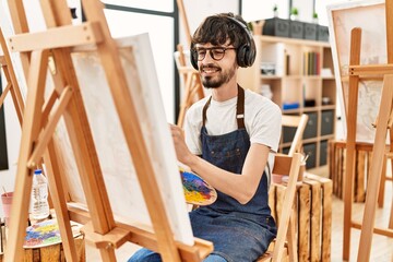 Obraz premium Young hispanic artist man listening to music drawing at art studio.