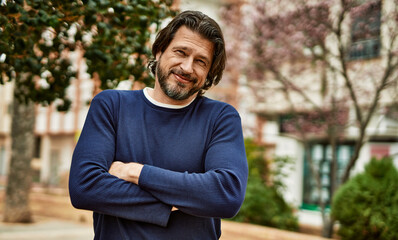 Middle age handsome man smiling with crossed arms outdoors at the park