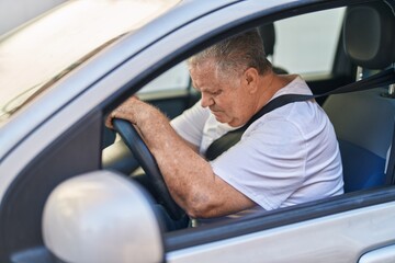 Middle age grey-haired man driving car at street