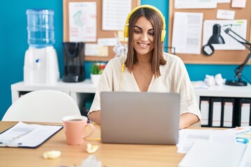 Young beautiful hispanic woman business worker listening to music working at office