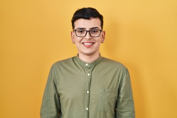 Non binary person standing over yellow background with a happy and cool smile on face. lucky person.