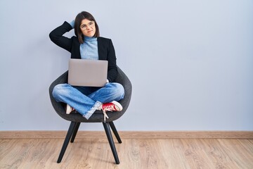 Young hispanic woman sitting on chair using computer laptop confuse and wondering about question....