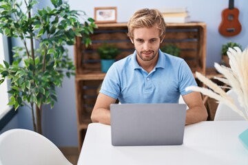 Young man using laptop sitting on table at home