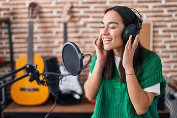 Young hispanic woman musician singing song at music studio