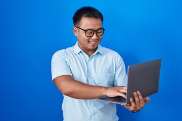 Chinese young man using computer laptop with a happy and cool smile on face. lucky person.