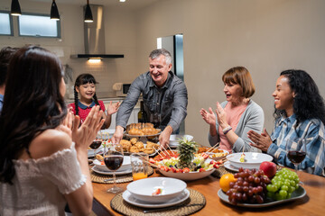 Multi-ethnic big family having dinner, enjoy evening party in house.