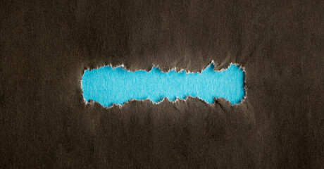 Torn black hole on blue paper background. As template for text or advertisement.