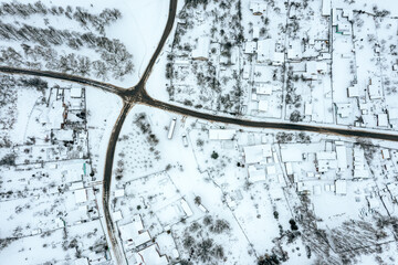 aerial drone photo looking down onto the rooftops of snow-covered suburban district