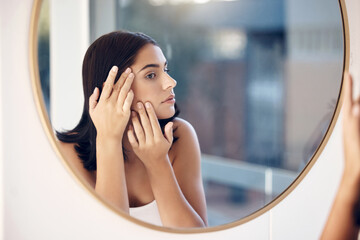 Skincare, facial and woman by a mirror to check for acne breakout or pimples while cleaning face in...