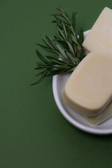 close up of handmade soap bars on white soap tray, green background