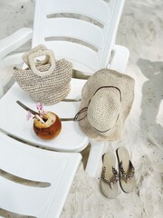 Summer background with straw hat, flip flops, wicker bag on sun lounger. Trendy summer holiday concept.