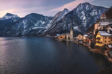 Landscape of Lake coast houses and Snowy Mountains Alps with cloudy sky in Hallstatt, Austria