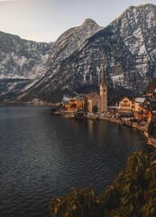 Landscape of Lake coast houses and Snowy Alps with cloudy sky in Hallstatt, Austria, vertical shot