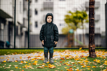A rejected foster child is standing on the street left alone on the rain.