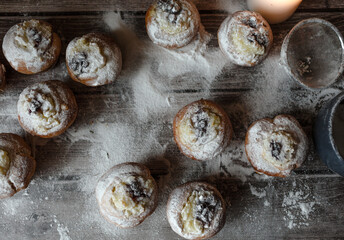 Muffins on a wooden table. Cupcakes with berries and cream sprinkled with powdered sugar. View from above.