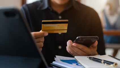 Businessman hand holding credit card and use laptop and smartphone in office.