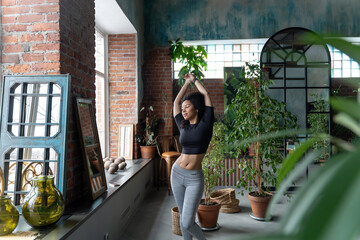 Slim Afro-American woman stretching at home or fitness studio in the morning. Studio decorated with...