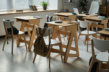 Modern empty classroom with wooden desks for students
