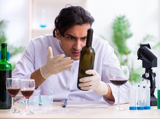 Male chemist examining wine samples at lab