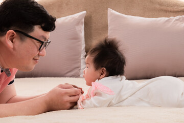 Selective focus father and healthy newborn 3 months baby eye contact together on bed, happy dad...