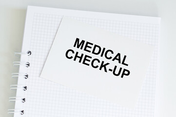 MEDICAL CHECK-UP text on a card on the background of a notebook on an isolated table, medical concept