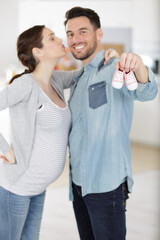 Fototapeta premium happy couple showing baby shoes at the camera