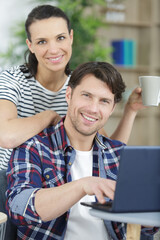 smiling husband and wife sit on couch accounting at home