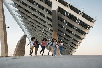 Group of students running underneath a modern solar panel structure