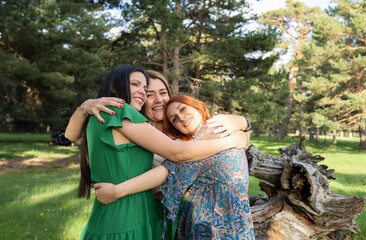 Group of three women embracing, connecting with nature in the forest. retreat