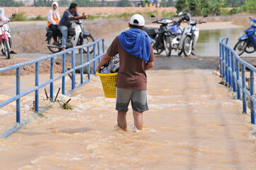 a man wading through the flood carrying a basket of clothes