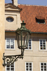 Fototapeta na wymiar Antique street lantern on wall in the old town of Prague, Czech Republic. Old street light against windows and roof tile