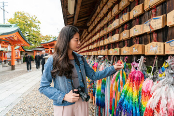 asian Japanese girl visitor holding and looking at colorful senbazuru paper cranes hanging under...