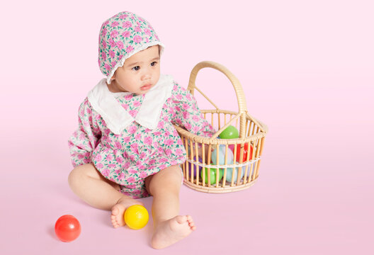 asian baby girl looking front and play toy ball