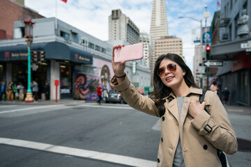 cheerful asian chinese girl tourist wearing sunglasses having video call with friend on cellphone...