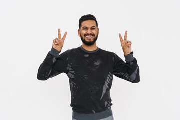 Young indian man with beard smiling and showing peace sign