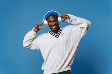 Naklejka premium Black young man gesturing and listening music with headphones